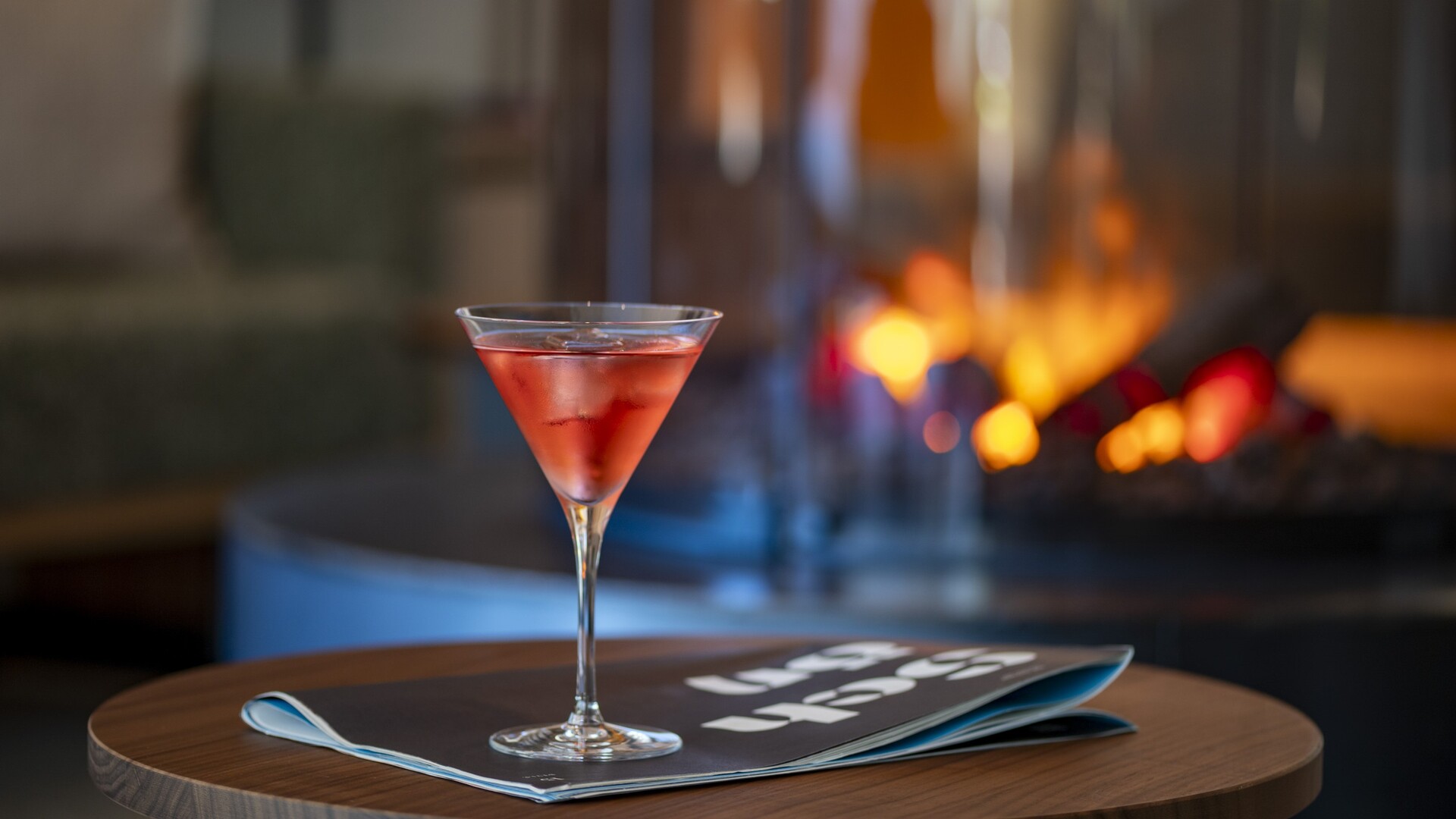 Roter Cocktail im Glas auf einem Holztisch vor dem Kaminfeuer im Seegut Zeppelin am Bodensee