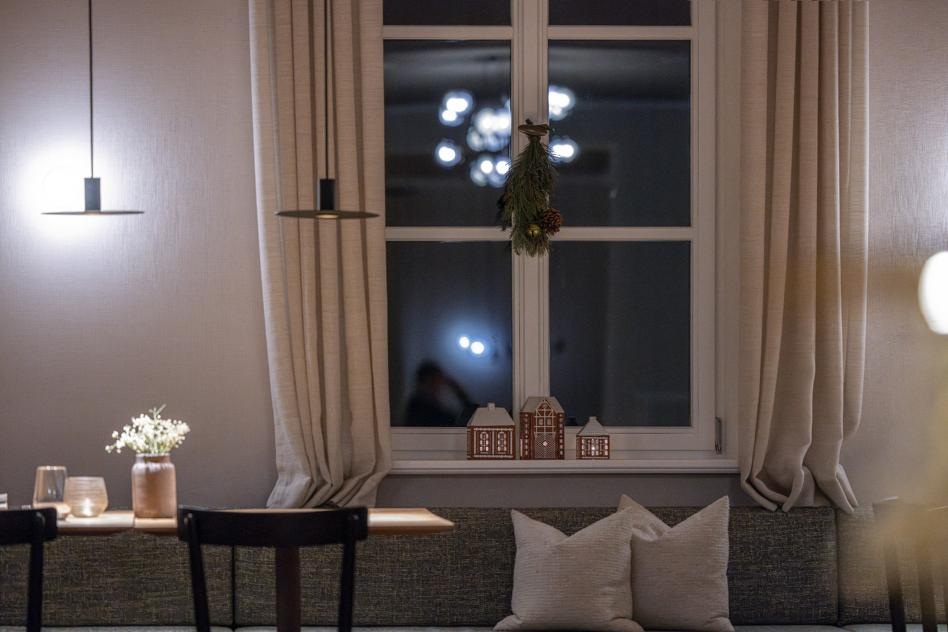 Fensterbank mit Kissen, Lebkuchenhäuschen und Tannenzweigen im Seegut Zeppelin am Bodensee am Abend
