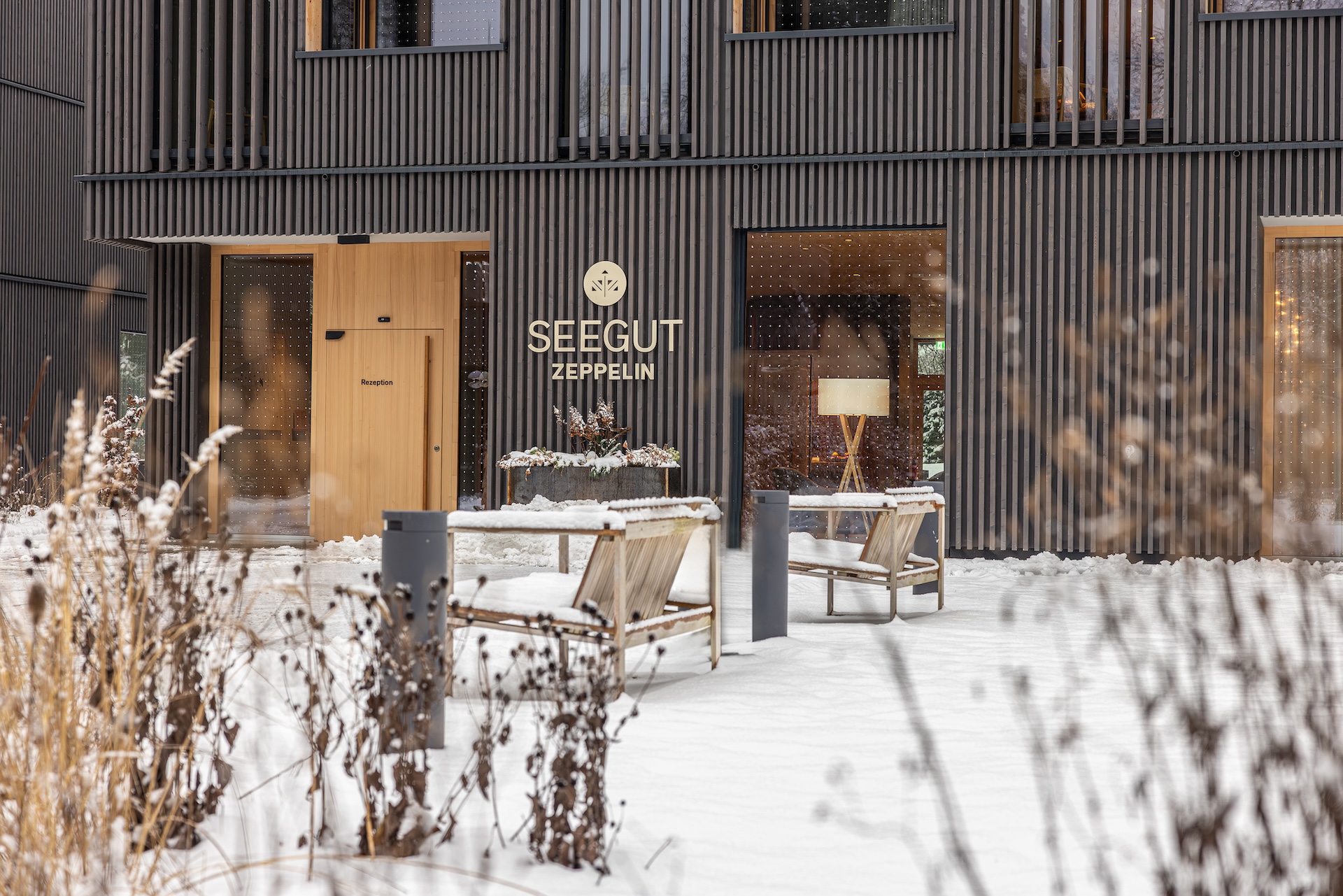 Eingang zum Neubau des Seegut Zeppelin im Winter, verschneiter Garten vor der Holzfassade am Bodensee