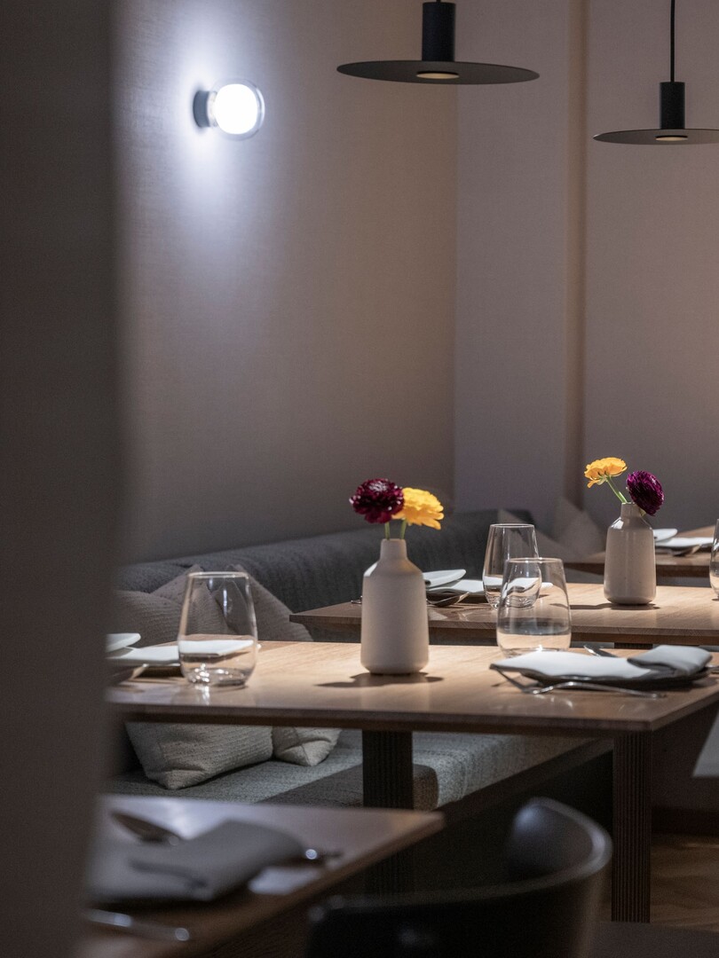 Restaurant Pinus im Seegut Zeppelin am Abend mit warmem Licht, gedeckten Tischen und Polsterbänken