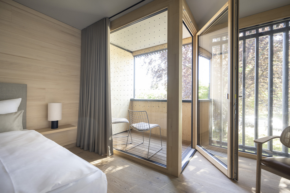 Gartenzimmer im Seegut Zeppelin mit Holzverkleidung und geöffneter Balkontür zur Loggia