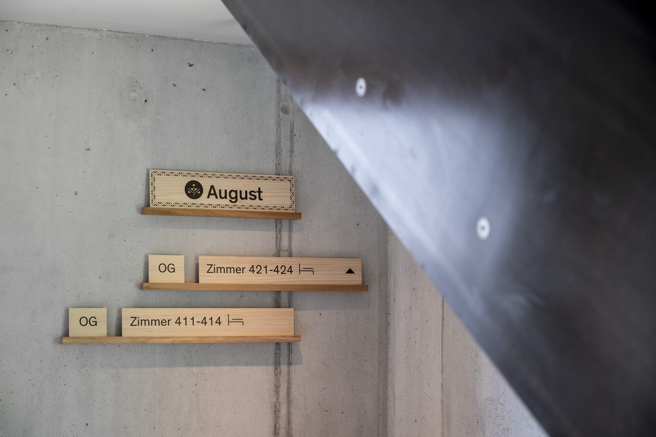 Wandschilder aus Holz mit der Aufschrift „August“ und Zimmernummern im Haus August des Seegut Zeppelin