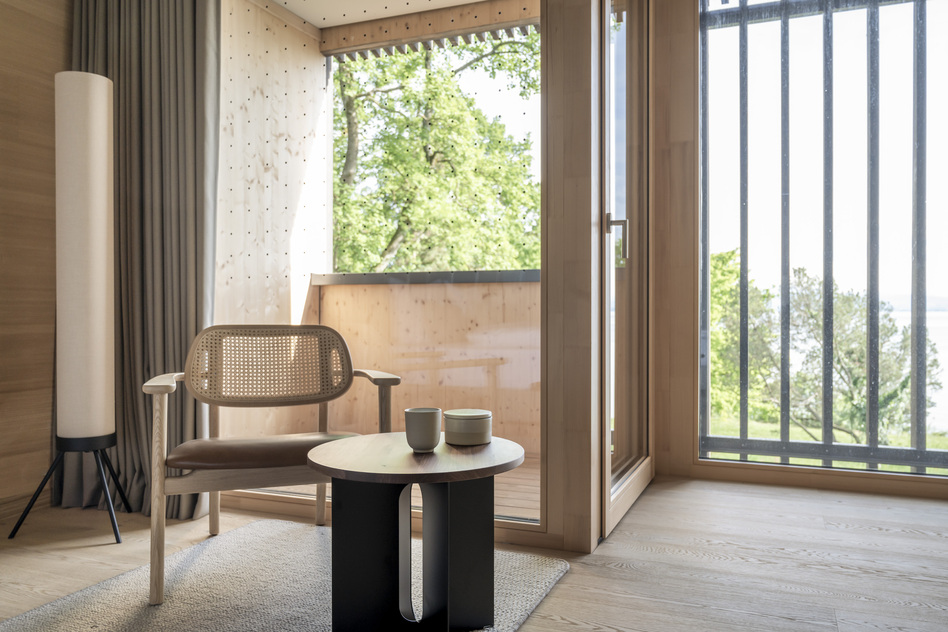 Waldzimmer im Seegut Zeppelin mit Rattan-Loungesessel, kleinem Beistelltisch und Balkon mit Blick ins Grüne