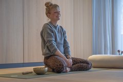 Yogalehrerin Birte Mittelmeier sitzt lachend auf der Matte im Yogaraum des Seegut Zeppelin am Bodensee