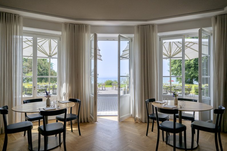 Speiseraum in der Villa Gminder des Seegut Zeppelin mit Erkerfenstern und Flügeltüren zur Terrasse mit Seeblick